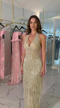 Front view of woman wearing Champagne Gold halter beaded fringe maxi evening gown