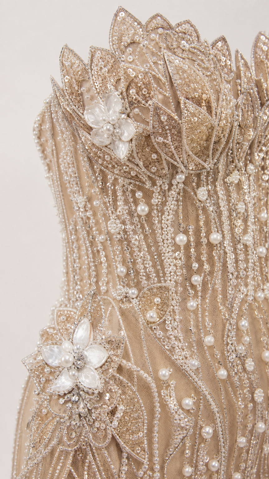 Close-up detail of 3D beaded floral appliques, pearl accents, and embroidery on sheer mesh