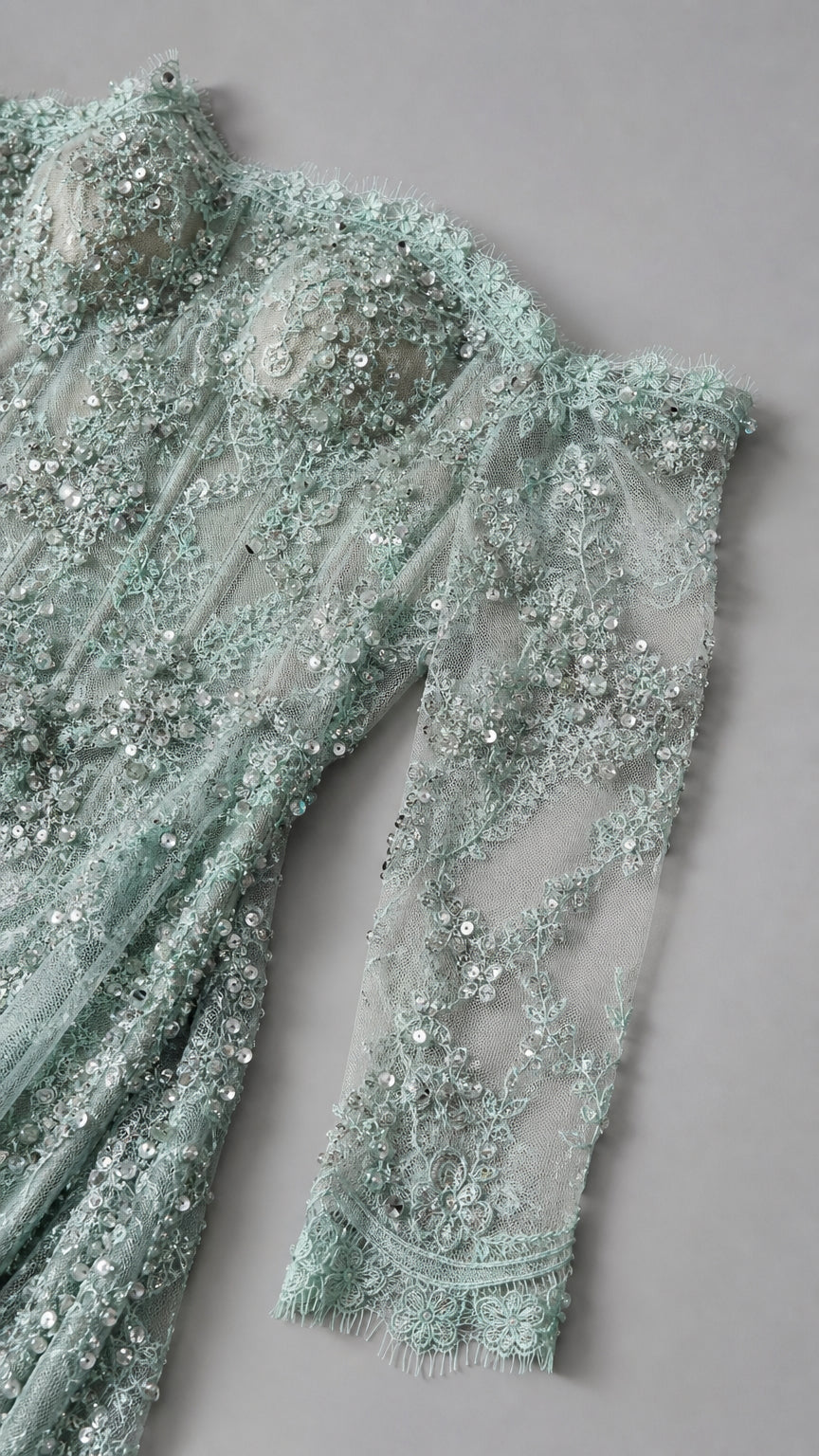 Close-up flat lay of sage green beaded lace corset bodice with sequins and sheer sleeves