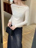 White fitted long-sleeved top with pleats and an off-the-shoulder neckline
